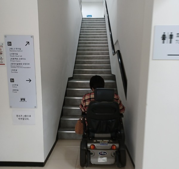 휠체어에 의존해 생활하는 박재숙(55·여)씨가 승강기가 없는 수원시립미술관 만석전시관을 찾았다가 2층을 올라가지 못하고 멈춰서 있다. 사진=소담장애인자립생활센터 제공