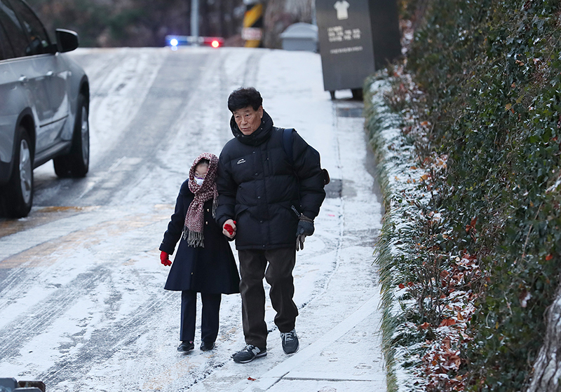▲ 새벽에 내린 눈으로 도로 곳곳이 얼어붙은 6일 오전 서울시내 한 이면도로로 한 어린이가 할아버지의 손을 잡고 등교하고 있다. 연합