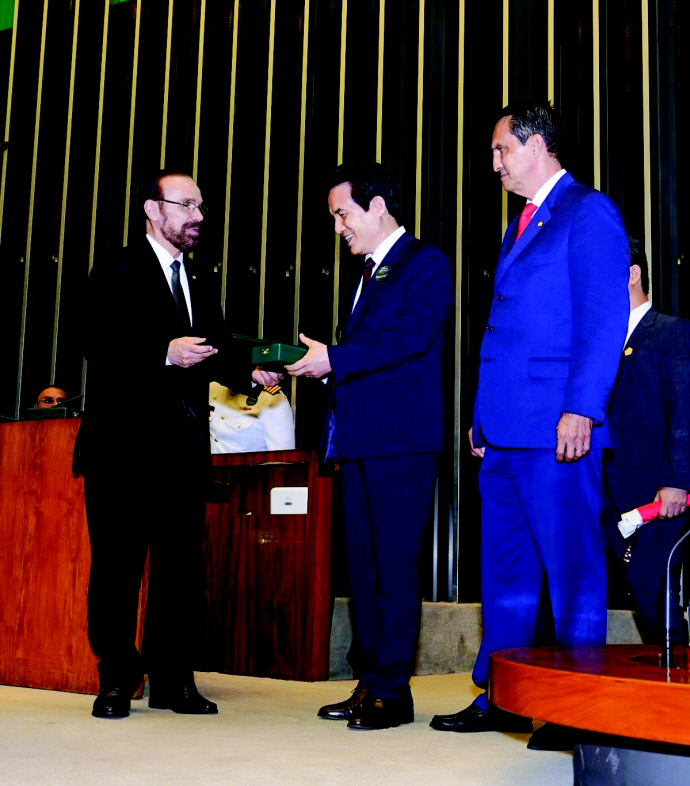 브라질 국회의사당에서 열린 시상식에서 링콘 포르텔라 연방하원의원 제1부의장(왼쪽)이 하나님의 교회 총회장 김주철 목사(중앙)에게 메달과 훈장증을 수여했다. 사진=하나님의 교회