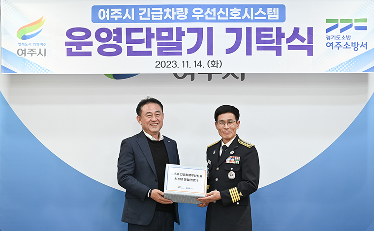 이충우 여주시장(왼쪽)이 오는 12월부터 시행하는 ‘실시간 긴급차량 우선신호 제어시스템’에 필요한 차량 단말기를 유재홍 여주소방서장에게 전달하고 있다. 사진=여주시청