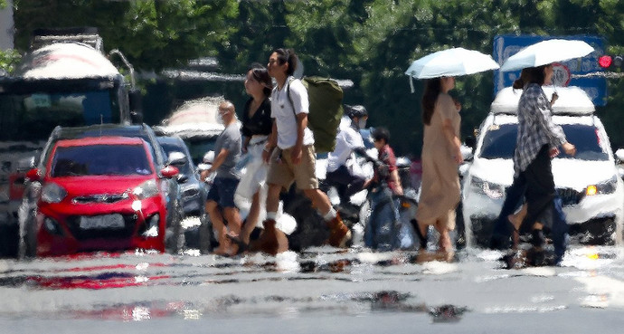 시민들이 열기로 가득한 도로 위를 걸어가고 있다. 연합뉴스