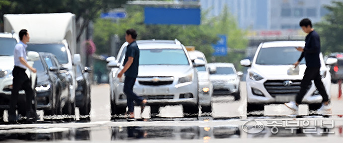 전국 대부분 지역에 폭염특보가 발효됨에 따라 폭염 위기경보 수준이 '심각' 단계로 상향된 가운데 27일 오후 수원시청 인근 횡단보도에서 시민들이 뜨거운 아스팔트에서 피어오르는 아지랑이 사이로 발걸음을 옮기고 있다. 김경민기자