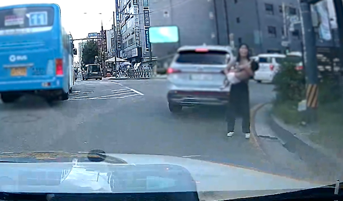 지난달 16일 오전 광명시 광명사거리의 모퉁이에서 SUV 차량에서 내린 한 여성이 열경련으로 쓰러진 아이를 들고 순찰차를 향해 달려오고 있다. 사진=광명경찰서
