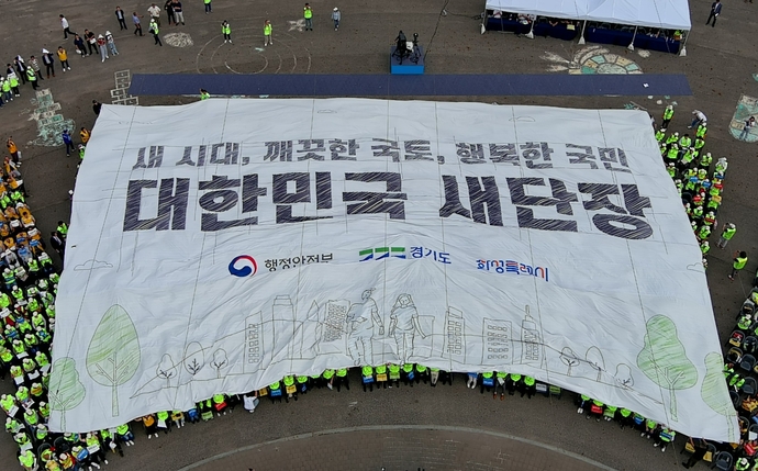 22일 화성시 궁평항 광장에서 열린 ‘대한민국 새단장 캠페인’에서 행사 참석자들이 대형 현수막을 머리 위로 넘기며 ‘대한민국 새단장’ 결의 퍼포먼스를 하고 있다. 사진=화성특례시청