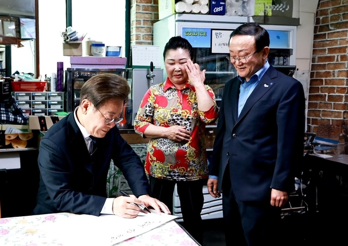 이재명 대통령이 지난 6월 13일 연천군 청산면을 방문해 농촌기본소득 시범사업 추진 상황을 점검하며 주민들과 환담한 뒤 기념 글을 남기고 있다. 사진=연천군청