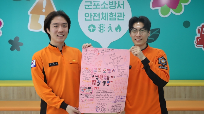 군포소방서 대원들이 ‘소방의 날’을 맞아 럭키유치원 어린이들이 손수 쓴 감사 롤링페이퍼를 들어 보이고 있다. 사진=군포소방서