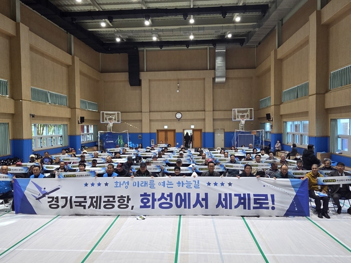 화성 화옹지구 서부발전협의회가 22일 화수초등학교에서 개최한 ‘화성 서부 지역 발전 세미나’ 참석자들이 경기국제공항 유치 관련 현수막을 들고 기념 촬영을 하고 있다. 사진=화성 화옹지구 서부발전협의회